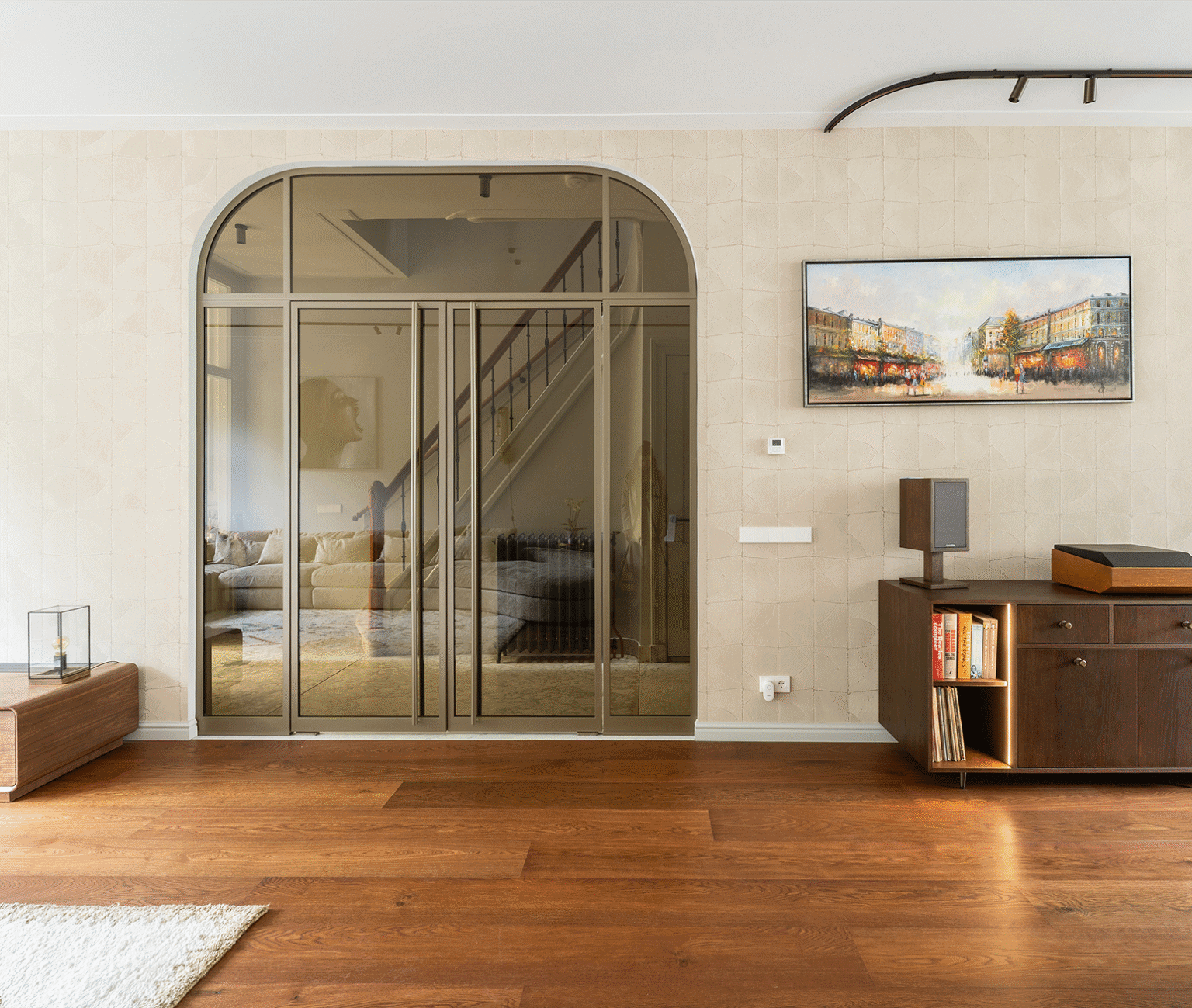 Moderne glazen binnendeur met houten vloer en kunstwerk in woonkamer.